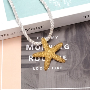 Golden starfish pendant necklace with white woven rope on vintage magazine