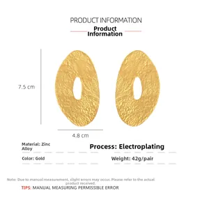 Detail of gold oversized irregular oval earrings featuring hammered metal texture and zinc alloy