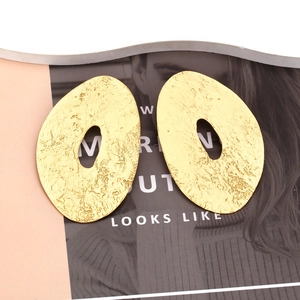 Vintage oversized gold irregular oval earrings with hammered texture on a fashion magazine