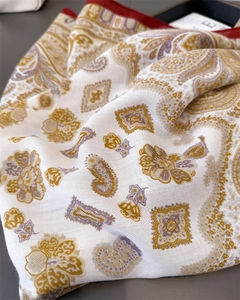 Dettaglio di sciarpa in seta con motivo paisley e morbida trama in oro e viola