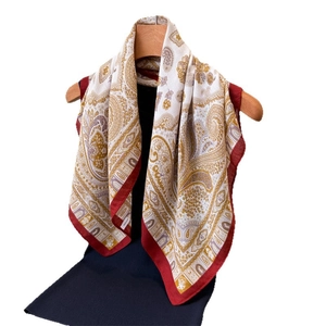 Elegante scialle con motivo paisley su manichino con bordi rossi e consistenza setosa