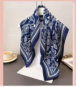 Detail view of the navy blue silk scarf with white paisley and floral print hanging elegantly