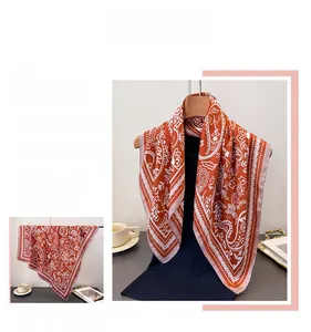 Detailed close-up of premium brick red paisley silk scarf with elegant floral patterns