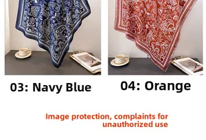 Detail of navy and orange silk square scarves with paisley patterns on white display