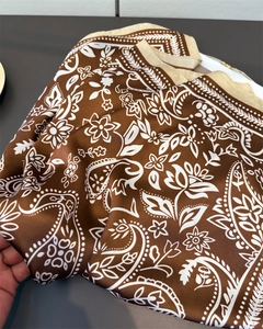 Detailed view of brown paisley print silk scarf with smooth satin finish and floral pattern