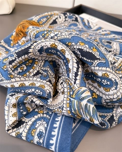 Detail shot of the paisley pattern and silk-like texture on this navy blue square scarf