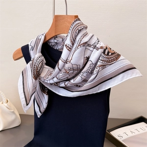 Elegant white silk scarf with nautical anchor and rope patterns on a hanger