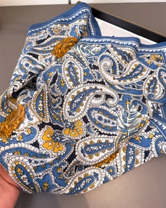 Detail view of paisley silk scarf with blue and yellow patterns on twill fabric texture
