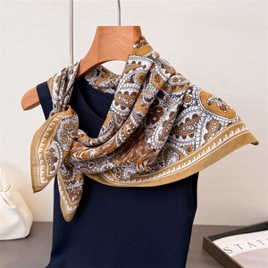 Caramel paisley cotton-linen feel square scarf tied on a deep blue vest with pearl bag