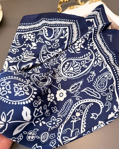 Detail of silk-like scarf showing paisley print, smooth texture and fine hem edges