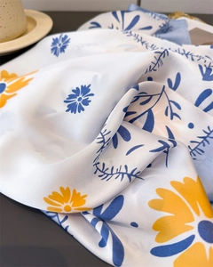 Detailaufnahme eines seidigen Seidenschals mit floralem Muster in Gelb und Blau