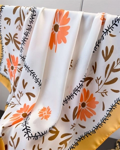 Detailansicht eines Seidenschals mit orangefarbenem Blumenmuster und gelber Saumkante
