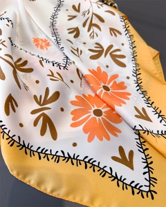 Detailansicht eines gelben Seidenschals mit Gänseblümchenmuster und Satin-Glanz-Textur