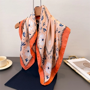 Eleganter orangefarbener Seidenschal mit Gänseblümchen-Print am Holzkleiderbügel