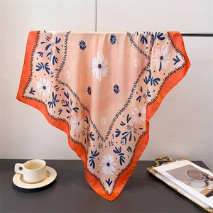 Detail eines Seidentuchs mit Gänseblümchenmuster und kräftigem orangefarbenem Rand