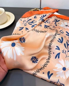 Nahaufnahme eines Seidenschals mit Gänseblümchen-Print und glatter Satin-Textur