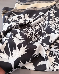 Close-up of black and white floral twill silk scarf with detailed botanical leaf pattern