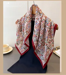 Detail of paisley print silk scarf with burgundy contrast borders on a black garment