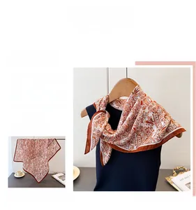 Close-up of elegant orange paisley silk scarf with refined brown stitched edge details