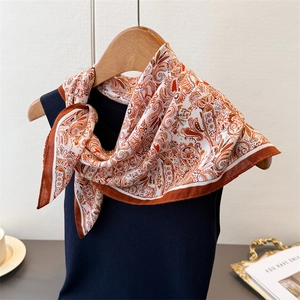 Detail of vintage paisley pattern on silky scarf styled on a blue tank top and wooden hanger