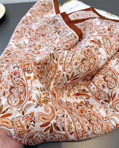 Close-up of vintage paisley pattern on soft silk-like fabric with warm orange tones
