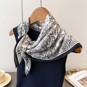 Detail of elegant black and white herringbone silk scarf tied on a navy knit vest