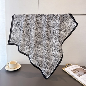 Elegant black and white paisley silk scarf displayed with home lifestyle props