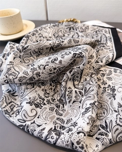 Detail of elegant black and white paisley silk scarf with refined hem and soft folds