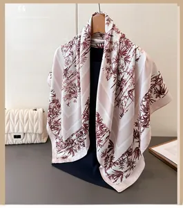 Detail of silk-feel square scarf with red bamboo prints on beige hanging on a wooden hanger