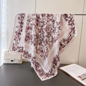 Detail of silk scarf with bamboo ink print and pink striped border on metal rack