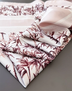 Detail of silk-like scarf featuring deep red floral patterns and satin texture