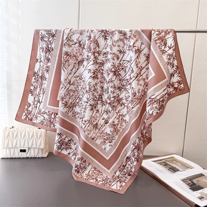 Detail of silk-like scarf featuring rust red bamboo prints on a white background