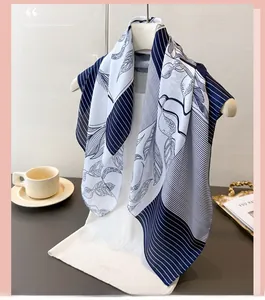 Detailed view of blue and white silk scarf with elegant leaf print hanging on display