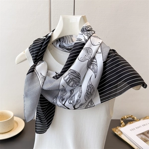 Detailed view of silk-like scarf with leaf texture and stripes draped over a white top