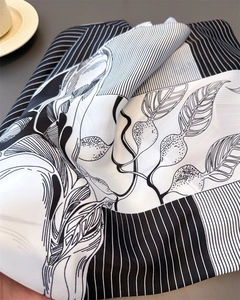 Detailed view of luxury silk scarf with elegant black and white leaf and stripe patterns