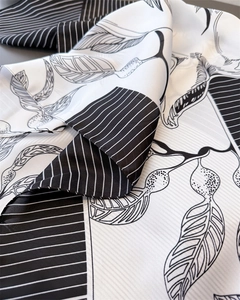 Detailed view of luxury silk scarf showing black and white leaf prints and striped patterns