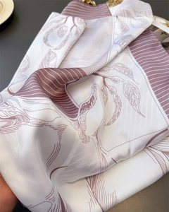 Macro view of silky satin scarf fabric with elegant leaf patterns and subtle drapery