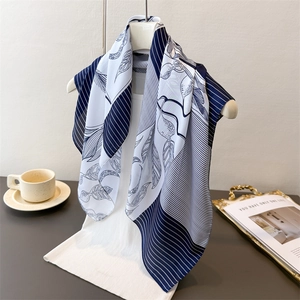 Elegant silk-like scarf with navy stripes and lemon print draped over a chic white outfit