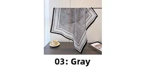 Macro detail of grey paisley pattern silk scarf with elegant black and white striped border