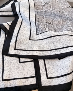 Detailed view of black and white scarf featuring classic paisley and geometric patterns