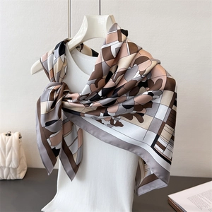 Détail d'un foulard en soie à imprimé floral géométrique sur un cintre blanc