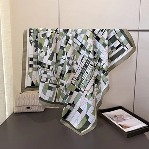 Détail d'un foulard carré en soie à imprimé floral et géométrique, drapé élégant