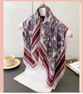 Detail of pink paisley silk-like scarf draped elegantly on a hanger with lifestyle props
