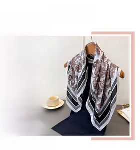 Detailed view of paisley silk scarf in deep brown and beige with satin finish texture