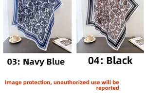 Detail of navy and black paisley silk-like scarves with geometric borders on a desk