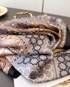 Detailed view of silk-like scarf featuring paisley prints and geometric patterns