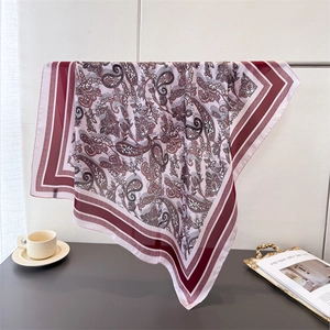 Elegant paisley print silk-feel square scarf with burgundy borders draped on a stand