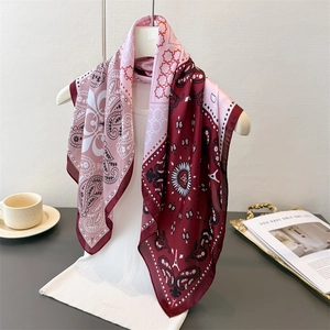 Silk-like pink and burgundy paisley print square scarf draped on a mannequin