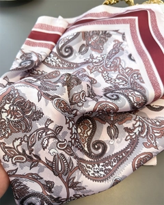 Detail view of paisley print satin scarf showing smooth texture and burgundy border