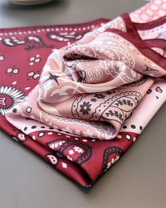 Close-up of silk-like satin scarf featuring red paisley patterns and luxury texture
